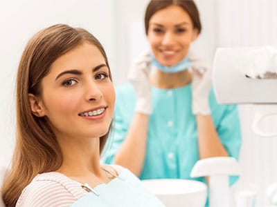 adult woman in braces smiling at dentist office