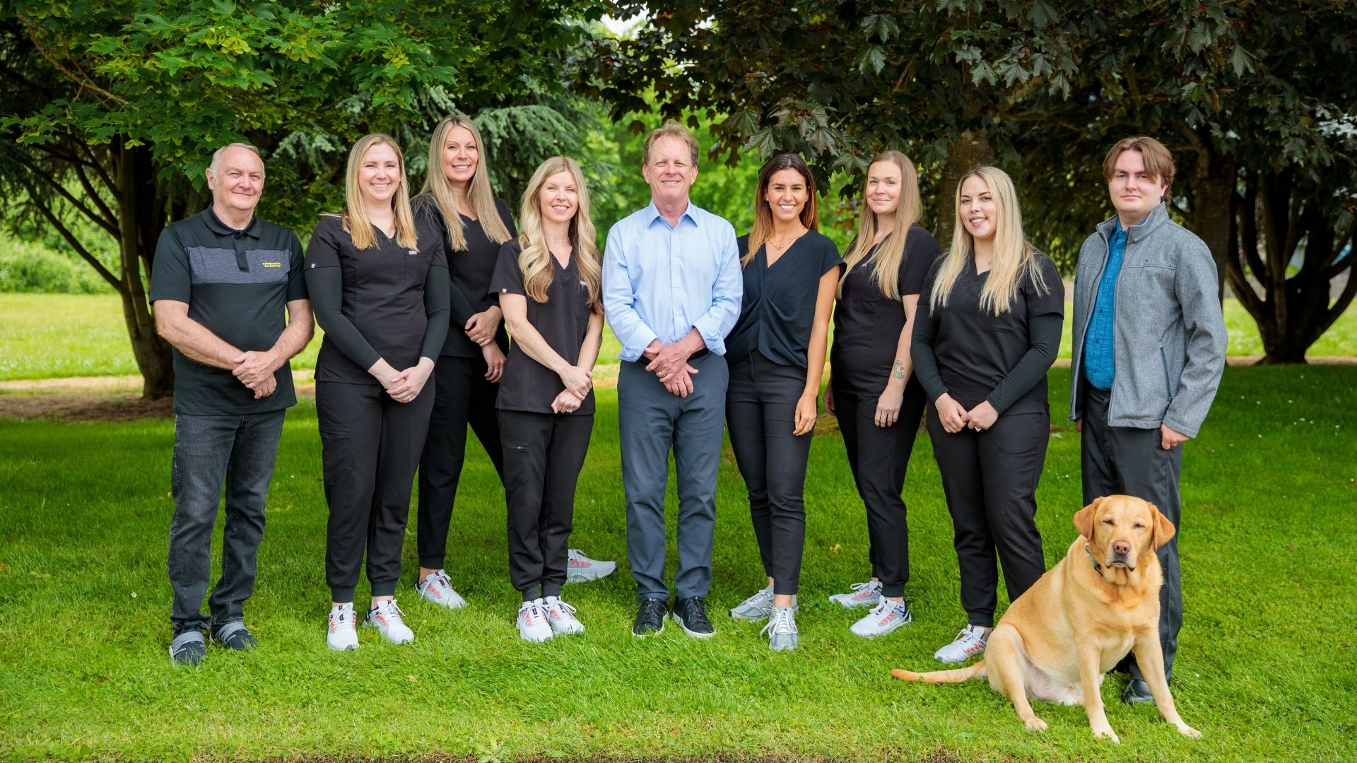 Dr. Gray Grieve standing outdoors with the orthodontic team and office dog in a park setting, Dr. W. Gray Grieve Orthodontics, Eugene, OR