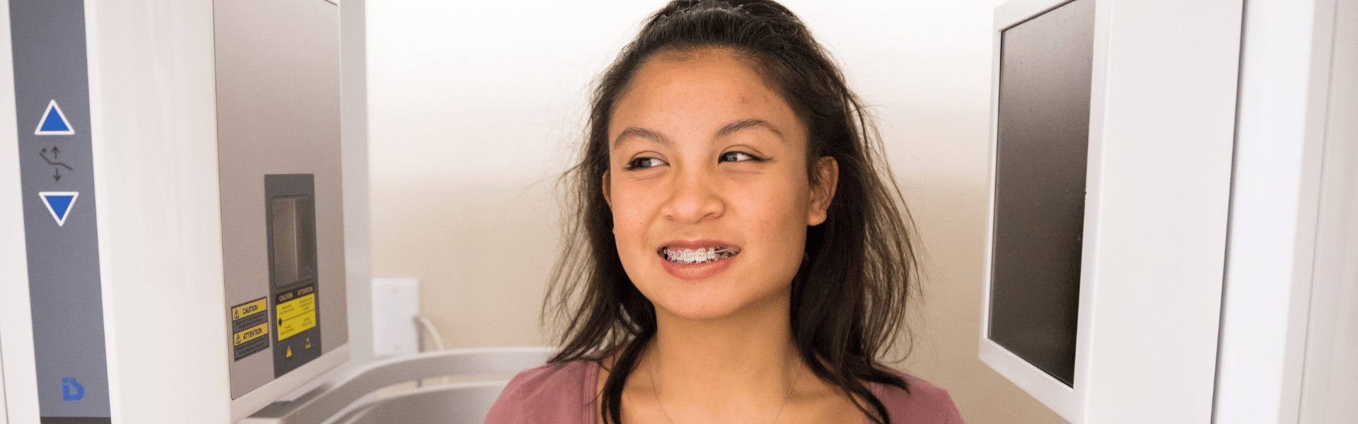 Smiling teen patient wearing metal braces while seated in an orthodontic treatment room, Dr. W. Gray Grieve Orthodontics, Eugene, OR