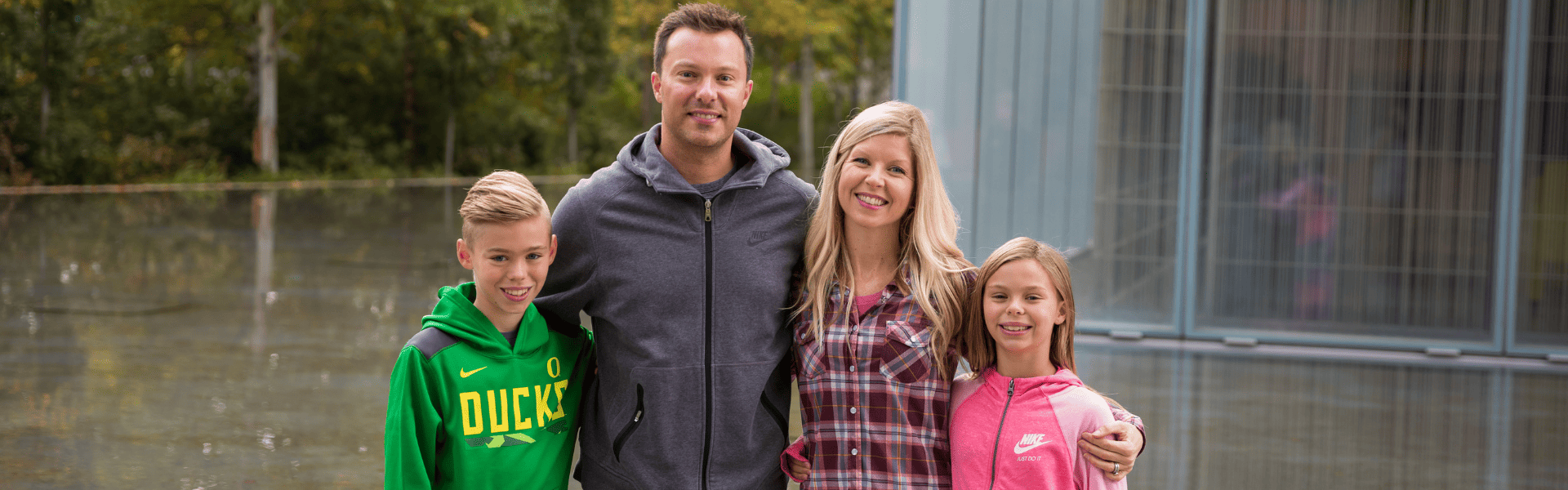 Smiling family of four standing together outdoors near water, Dr. W. Gray Grieve Orthodontics, Eugene, OR