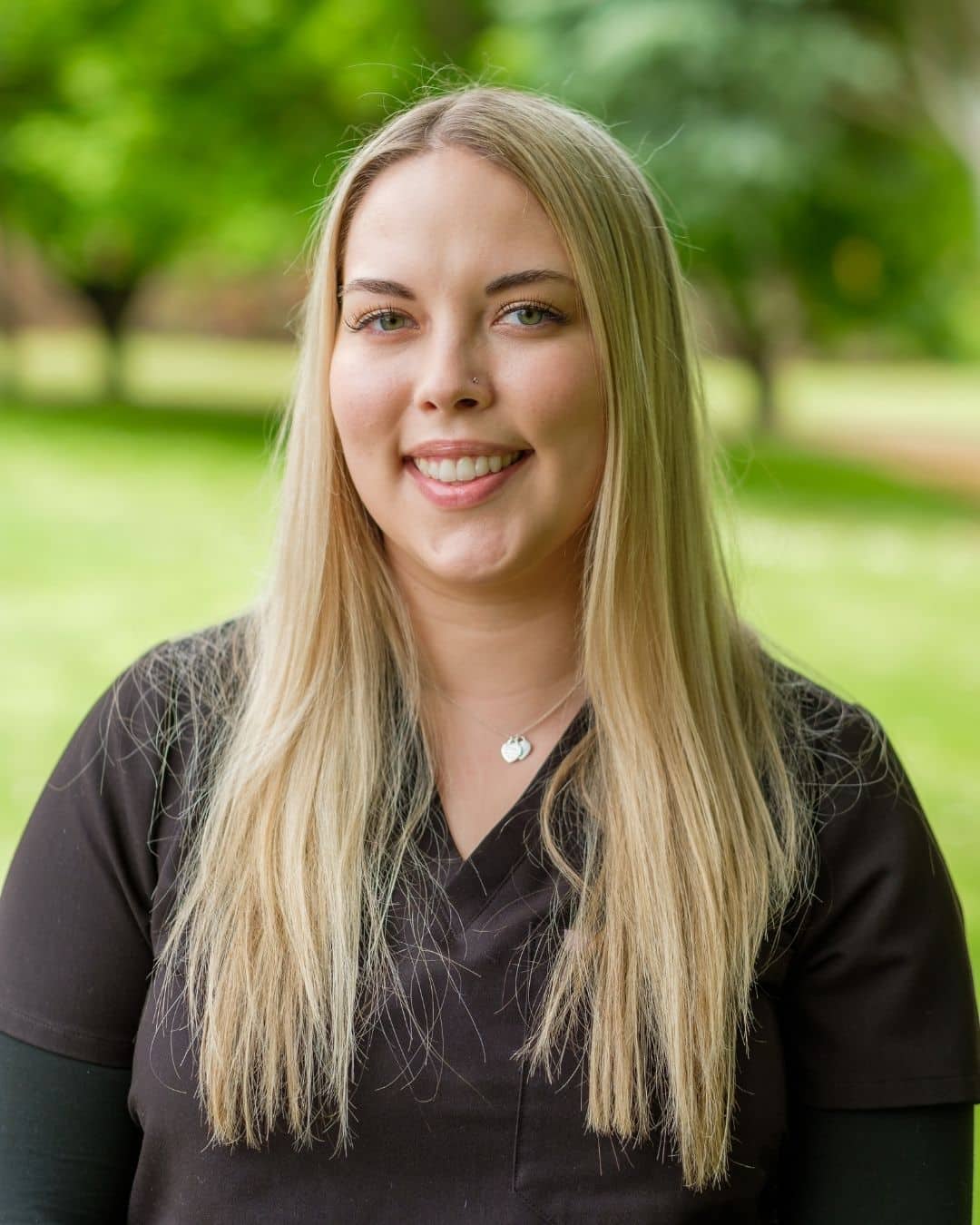 Portrait of Stacey, orthodontic assistant, smiling outdoors in black scrubs, Dr. W. Gray Grieve Orthodontics, Eugene, OR