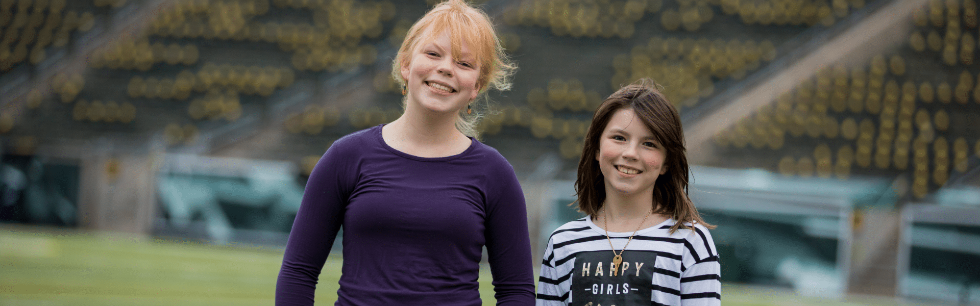 Two smiling child patients standing together on a football field, Dr. W. Gray Grieve Orthodontics, Eugene, OR