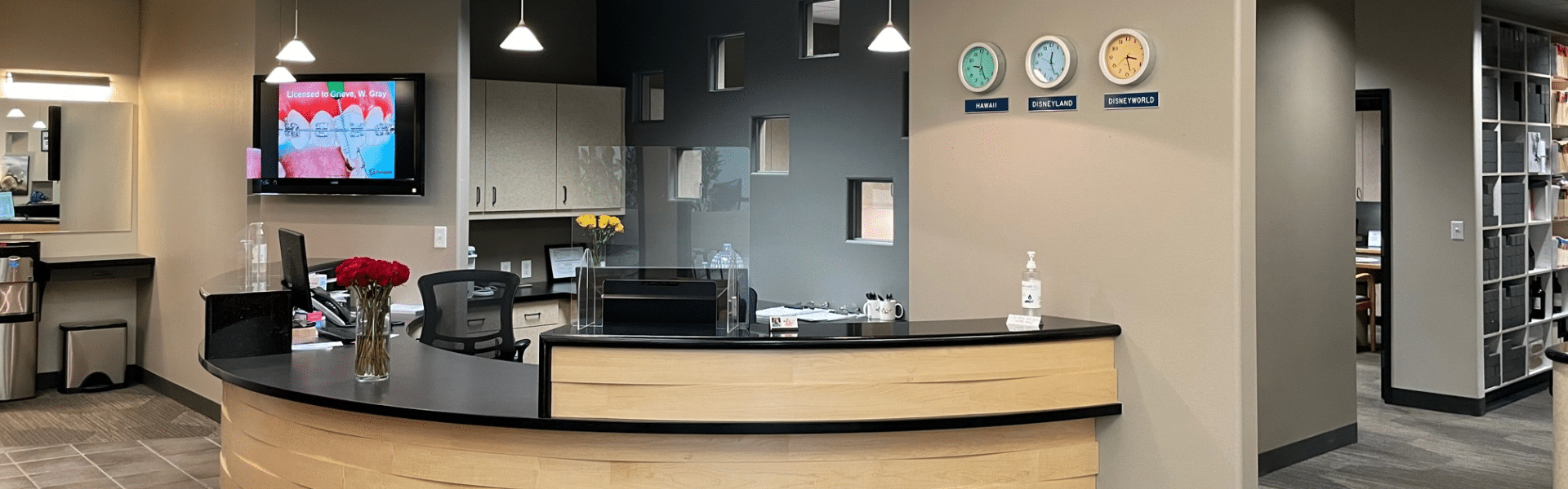 Orthodontic office front desk and reception area with clocks, flowers, and patient check-in counter, Dr. W. Gray Grieve Orthodontics, Eugene, OR