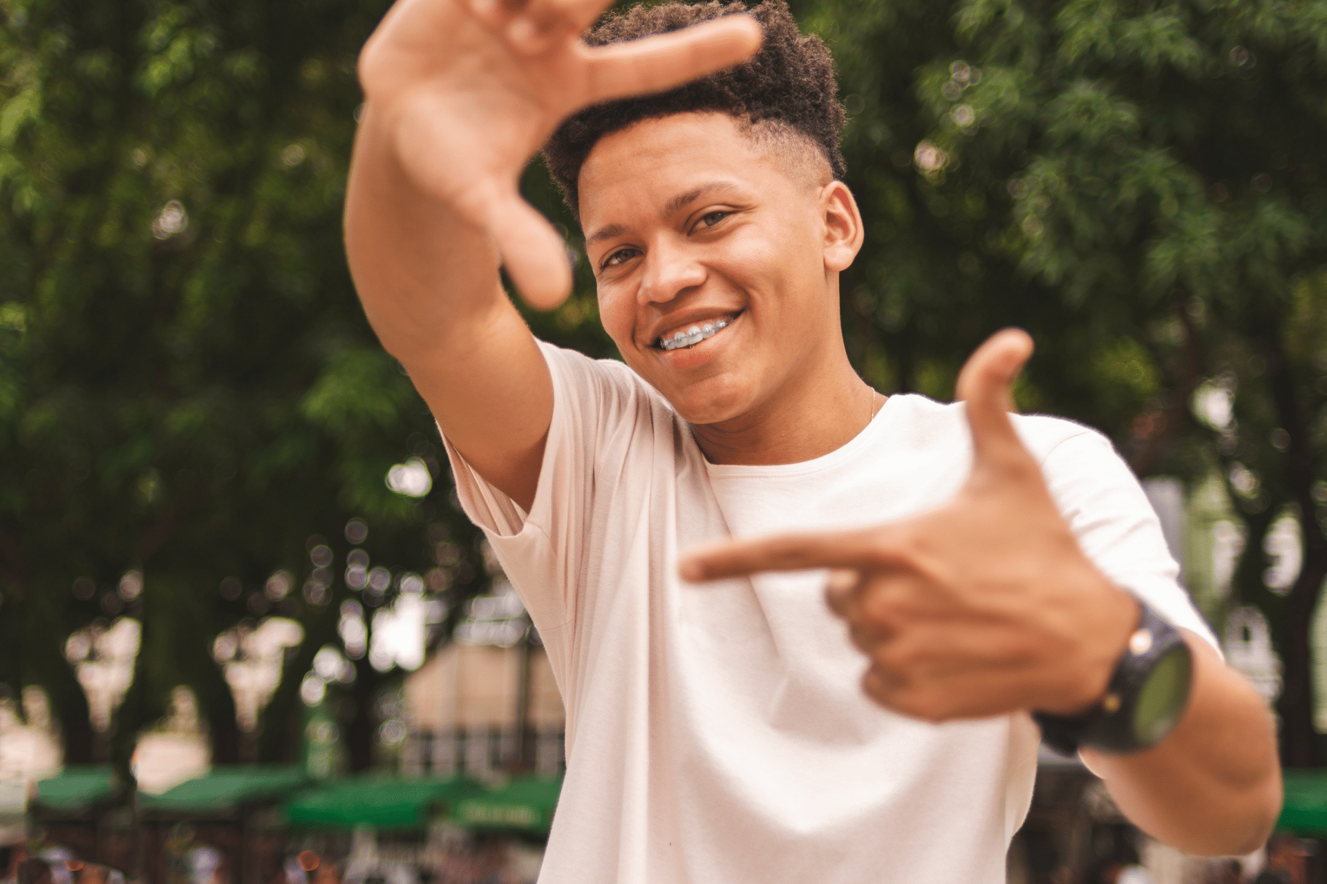 Smiling young man wearing braces and gesturing with his hands outdoors