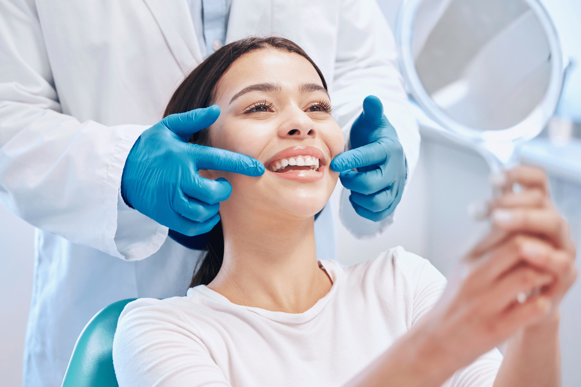 Patient holding a mirror during a clinical smile evaluation with an orthodontist